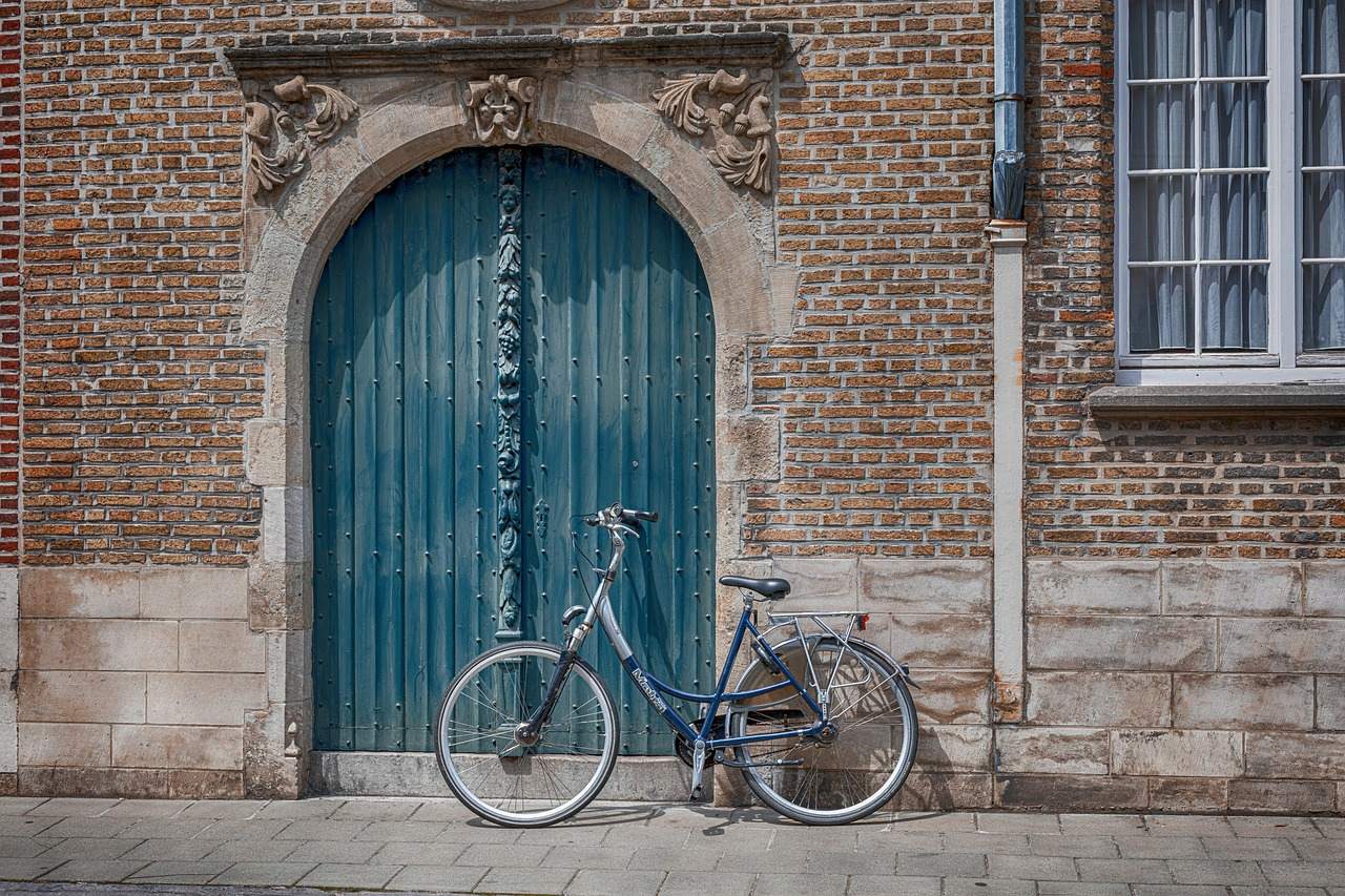 A carved stone doorway set in an old brick facade, with a bicycle leaning beside it